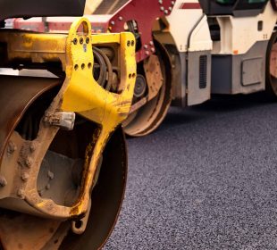Close-up of road rollers compacting fresh asphalt during road construction