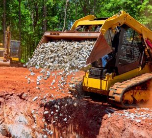 Unloading gravel with an excavator bucket skid steer loader during construction project