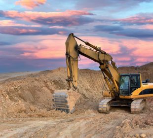 Excavator on sunset background. Open-pit mining. Backhoe dig ground in quarry. Heavy construction equipment on excavation on construction site. Excavator on groundwork on dramatic twilight.
