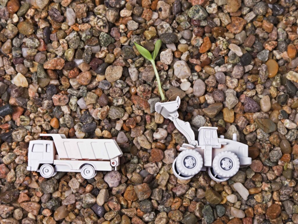 truck and excavator toys on pebbles to signify eco friendly construction with trs equipment rental