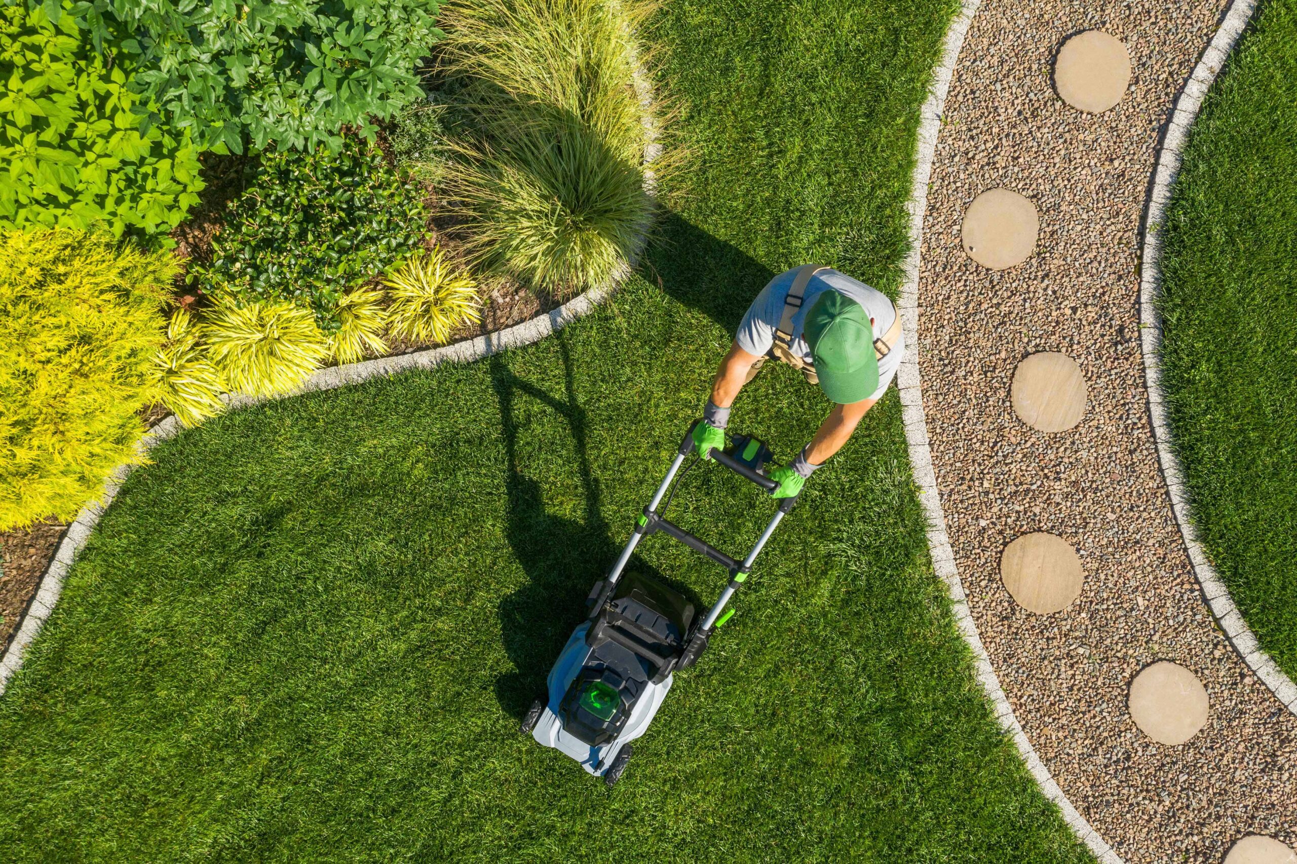 a man pushing a lawn mower as part of his landscaping project with the rented equipment from trs equipment rental