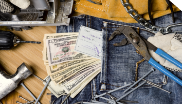 cash and small tools on a table representing construction equipment