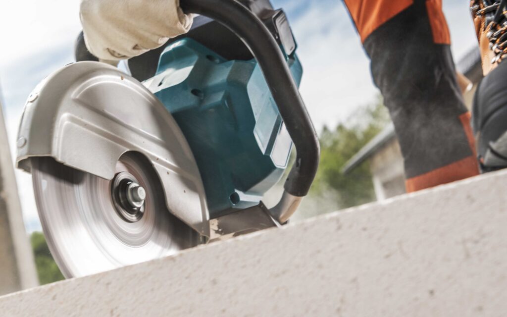 Concrete saw cutting through concrete during construction, illustrating a concrete saw vs. jackhammer comparison for concrete cutting and demolition.