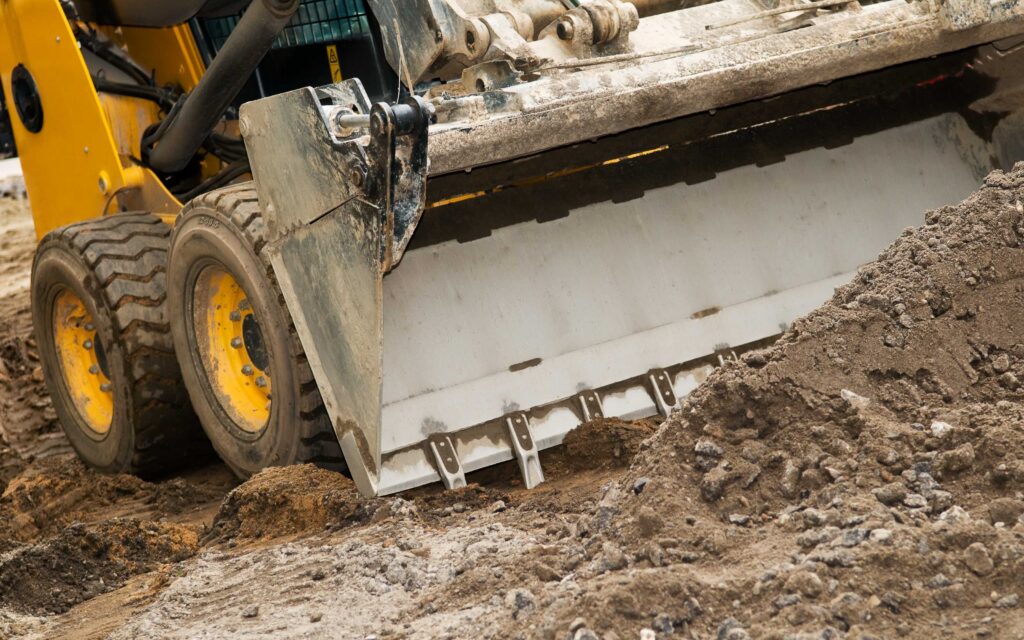 Storm cleanup equipment skid steer loader removing mud and debris after a storm in Tucson.