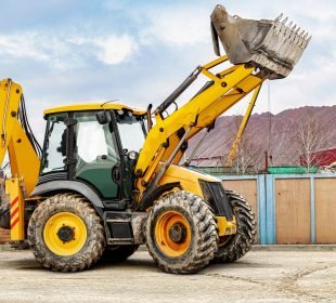 Backhoe rental driving in a construction yard