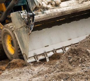 Storm cleanup equipment skid steer loader removing mud and debris after a storm in Tucson.